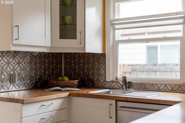 kitchen with butcher block countertops, white cabinets, decorative backsplash, and a sink