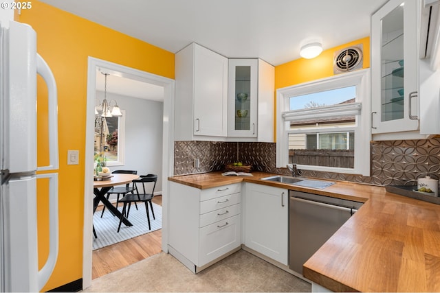 kitchen with visible vents, a sink, freestanding refrigerator, butcher block counters, and dishwasher