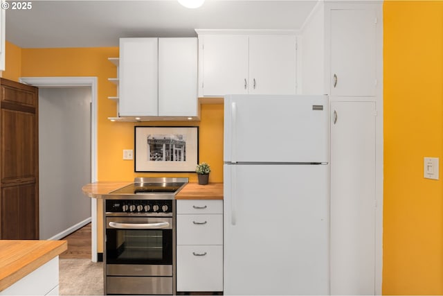 kitchen with wall oven, white cabinetry, butcher block countertops, and freestanding refrigerator