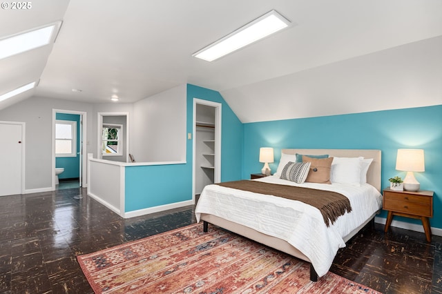 bedroom with lofted ceiling with skylight and baseboards