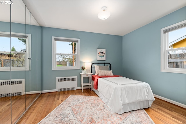 bedroom featuring radiator, baseboards, and wood finished floors