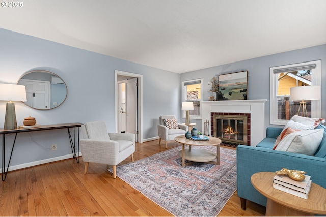 living room featuring a fireplace with flush hearth, light wood-style flooring, and baseboards