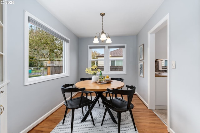 dining area with baseboards, light wood-style floors, and a chandelier