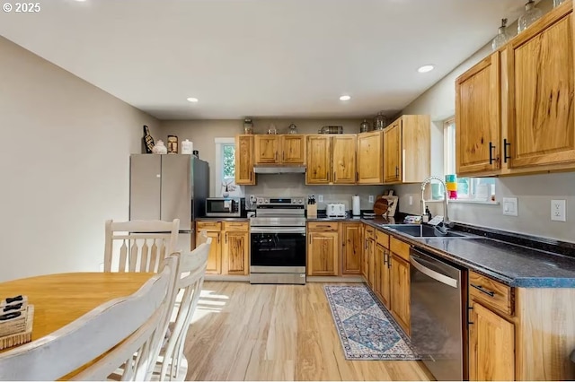 65121 E Lupine Dr, Rhododendron, OR 97049 - kitchen featuring stainless steel appliances, under cabinet range hood, a sink, dark countertops, and light wood-style flooring