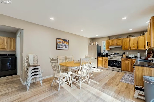 65121 E Lupine Dr, Rhododendron, OR 97049 - kitchen featuring appliances with stainless steel finishes, washer / clothes dryer, a sink, under cabinet range hood, and light wood finished floors