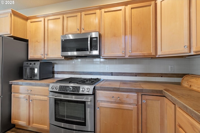 5779 NE Voyage Way, Lincoln City, OR 97367 - kitchen featuring decorative backsplash, a textured ceiling, light brown cabinetry, tile counters, and stainless steel appliances