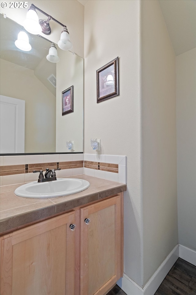 5779 NE Voyage Way, Lincoln City, OR 97367 - bathroom with backsplash, vanity, wood-type flooring, and vaulted ceiling