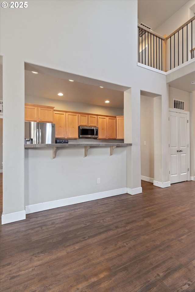 5779 NE Voyage Way, Lincoln City, OR 97367 - kitchen with stainless steel appliances, a kitchen breakfast bar, dark hardwood / wood-style floors, kitchen peninsula, and light brown cabinetry