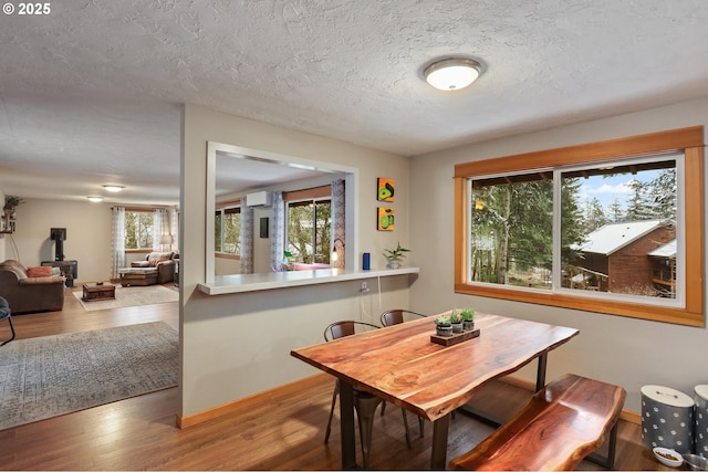 dining space featuring a wall mounted air conditioner, wood-type flooring, and a textured ceiling