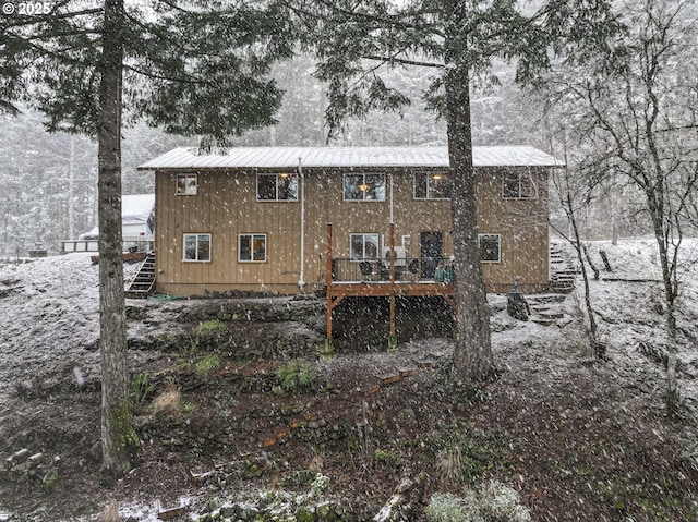 snow covered back of property featuring a deck