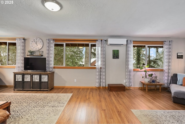 living room featuring hardwood / wood-style flooring, a wall mounted air conditioner, and a textured ceiling