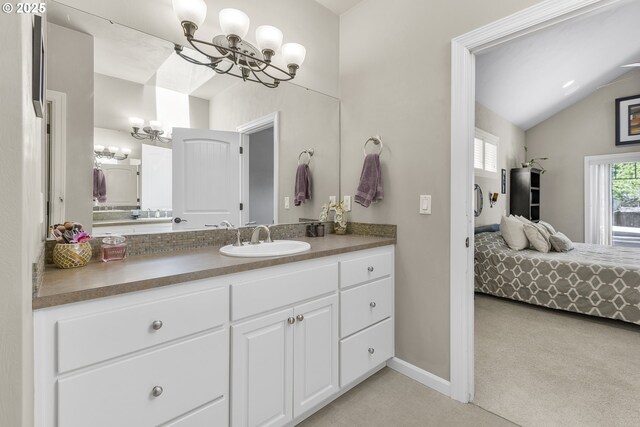 ensuite bathroom featuring an inviting chandelier, vanity, baseboards, ensuite bathroom, and vaulted ceiling