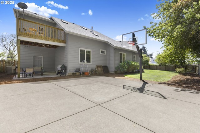 back of house with fence, a balcony, roof with shingles, a patio area, and a yard