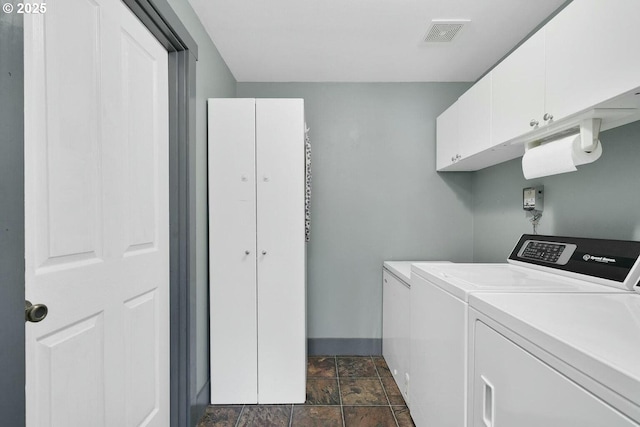 laundry room with separate washer and dryer and cabinets