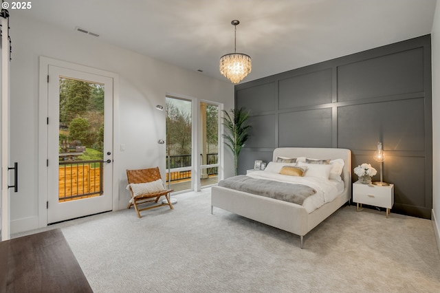 carpeted bedroom featuring access to outside and a chandelier