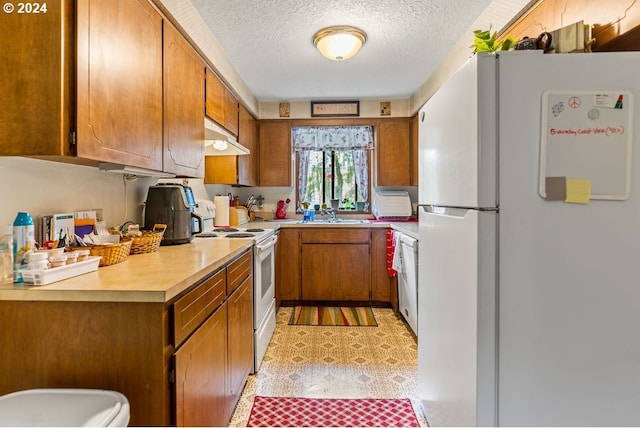 8050 SW 103rd Ave, Beaverton, OR 97008 - kitchen featuring white appliances, a textured ceiling, brown cabinets, light countertops, and under cabinet range hood