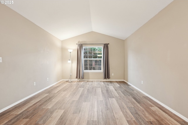 empty room with vaulted ceiling and light wood-type flooring