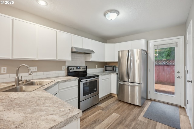 kitchen with sink, white cabinetry, a textured ceiling, appliances with stainless steel finishes, and light hardwood / wood-style floors