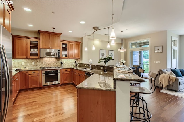 kitchen with pendant lighting, a kitchen breakfast bar, dark stone counters, kitchen peninsula, and stainless steel appliances