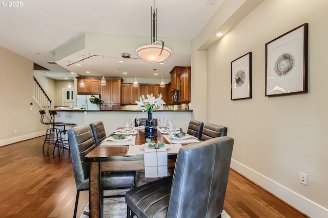 dining space featuring stairway, wood finished floors, and baseboards