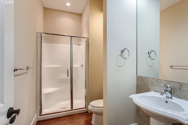 bathroom with toilet, a shower with door, sink, and hardwood / wood-style floors