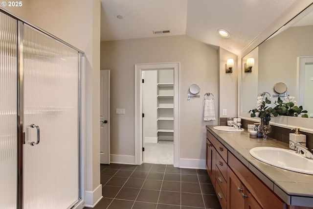 bathroom with vaulted ceiling, visible vents, a shower stall, and a sink