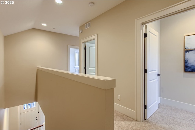 corridor with light colored carpet and vaulted ceiling