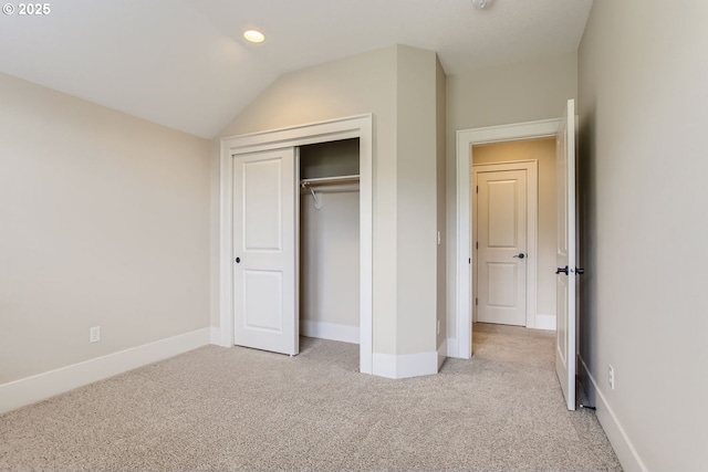 unfurnished bedroom featuring recessed lighting, a closet, baseboards, light colored carpet, and vaulted ceiling