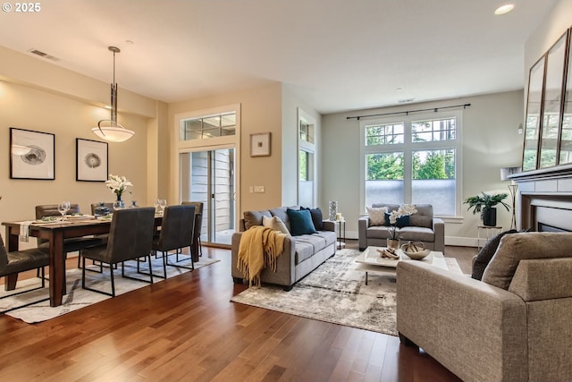 living area with visible vents, baseboards, dark wood finished floors, and a fireplace