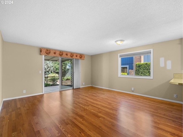 spare room with a textured ceiling, baseboards, and wood finished floors