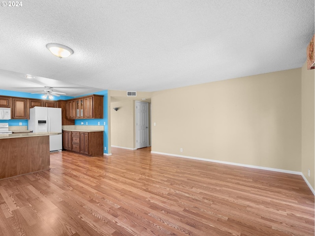 kitchen with white appliances, light wood-style flooring, light countertops, and open floor plan