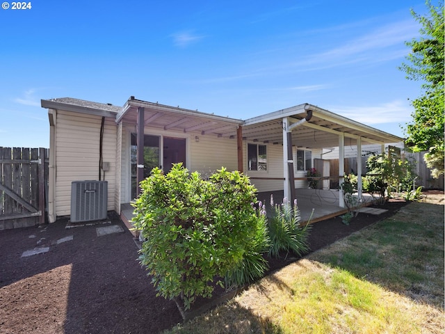 back of house featuring a yard, central AC unit, and fence