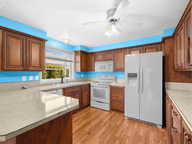 kitchen with light countertops, white appliances, a sink, and light wood-style flooring