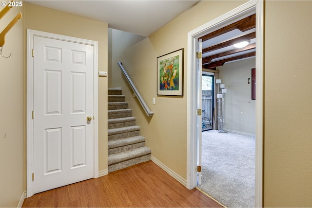 stairs featuring beamed ceiling, baseboards, and wood finished floors