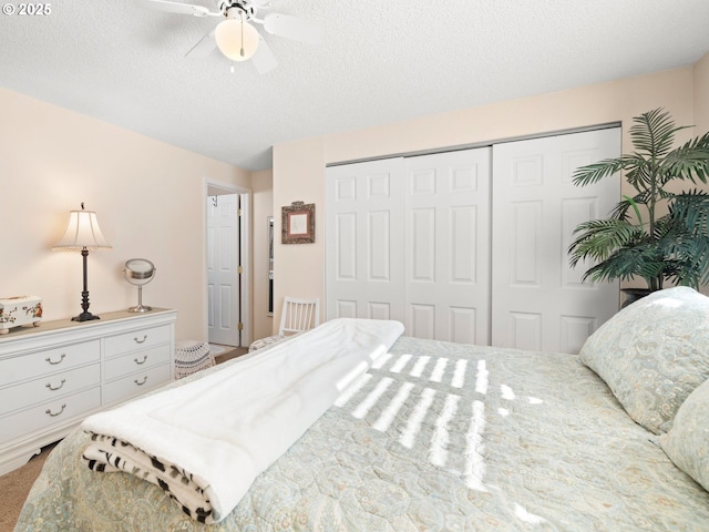 carpeted bedroom with a closet, a textured ceiling, and ceiling fan