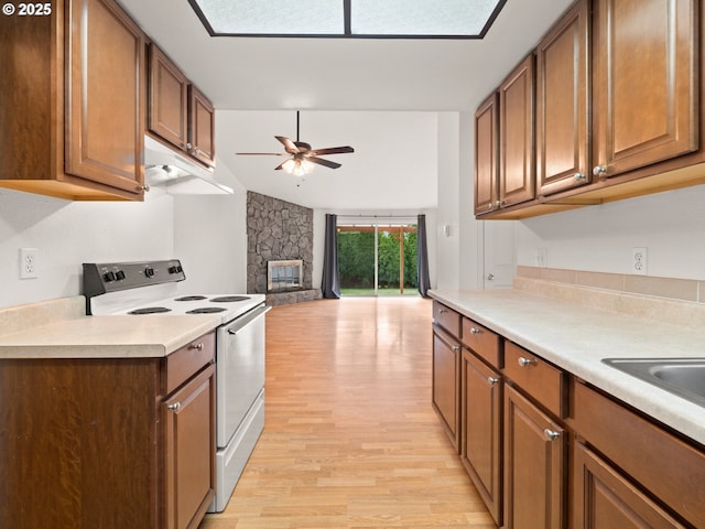 kitchen with white electric range, light wood-style floors, a fireplace, light countertops, and ceiling fan