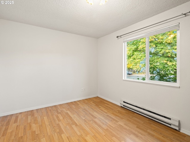 empty room with light wood-style flooring, baseboards, baseboard heating, and a textured ceiling