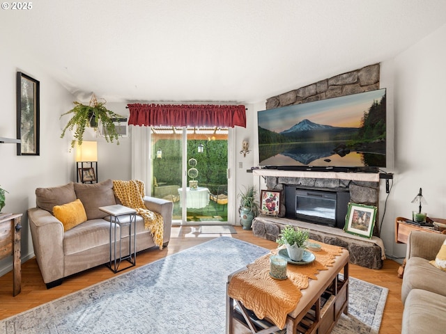 living area with a stone fireplace and wood finished floors