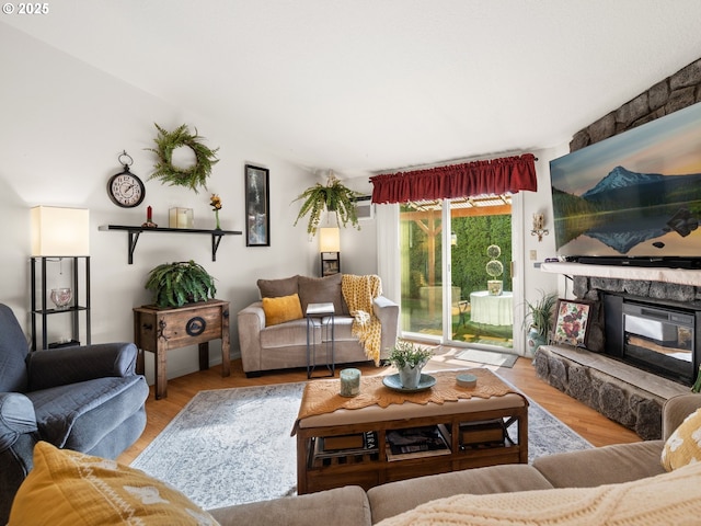 living area featuring a stone fireplace and wood finished floors