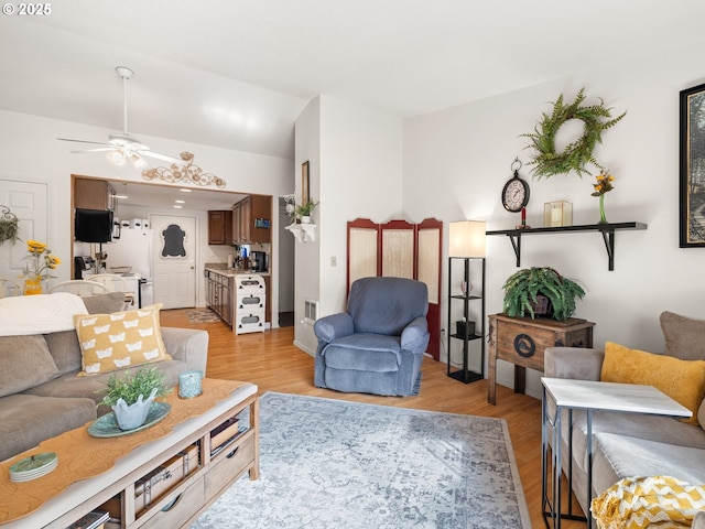 living room with ceiling fan, visible vents, and light wood-style flooring