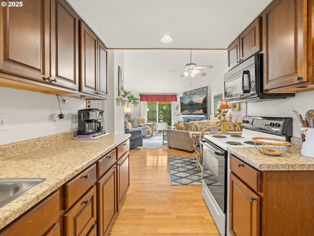 kitchen with light wood finished floors, black microwave, open floor plan, light countertops, and electric range