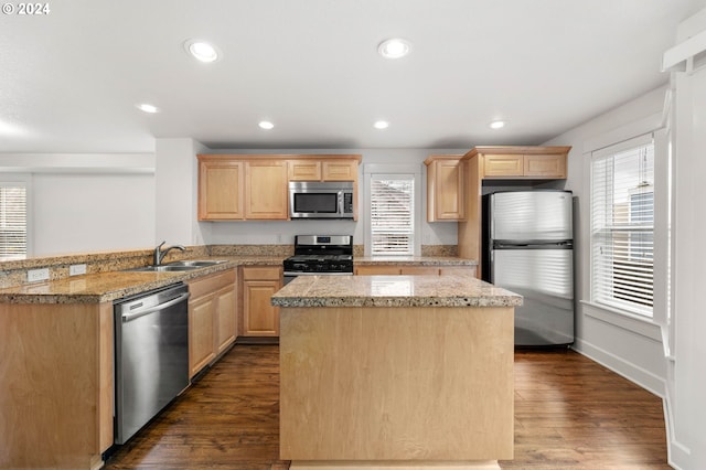 kitchen with dark wood-style flooring, stainless steel appliances, light brown cabinetry, a sink, and a peninsula