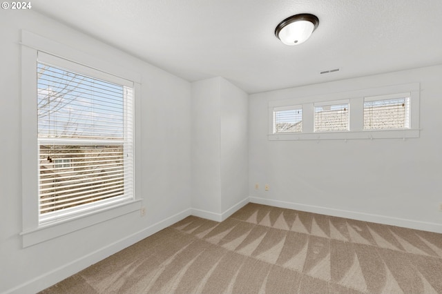 spare room featuring carpet flooring, visible vents, and baseboards