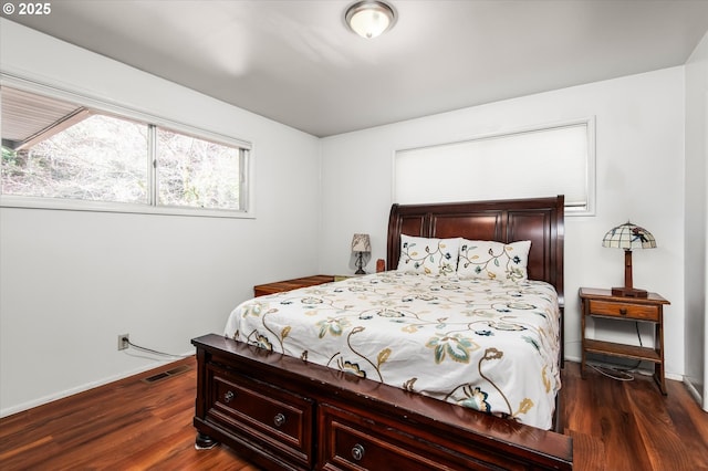 bedroom with baseboards, visible vents, and dark wood finished floors