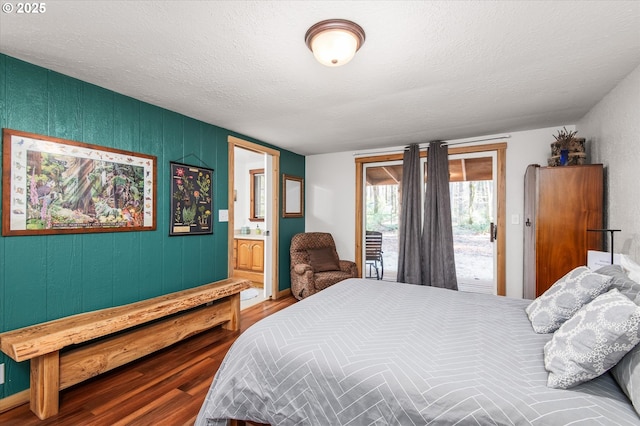 bedroom featuring access to exterior, connected bathroom, a textured ceiling, and wood finished floors