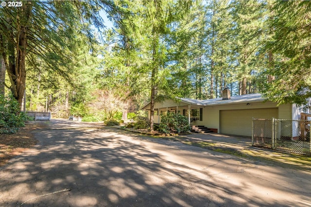 view of front of property with driveway, a chimney, an attached garage, and fence