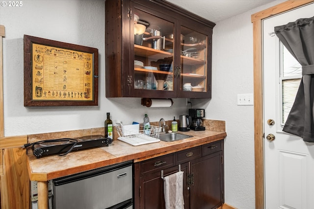 bar with a textured wall, wet bar, a sink, and a textured ceiling