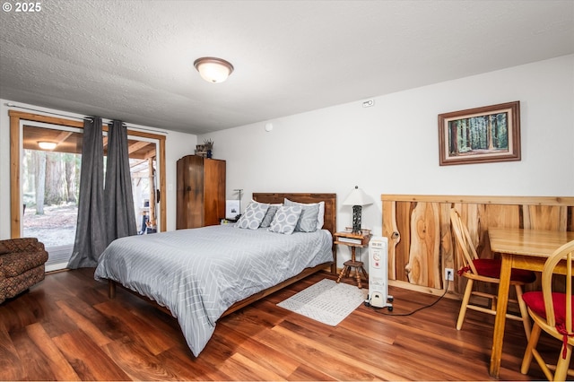 bedroom with access to exterior, a textured ceiling, and wood finished floors