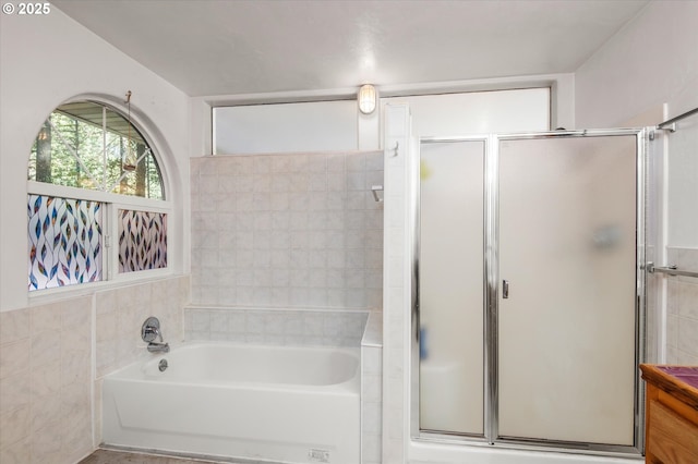 bathroom featuring tile walls, a shower stall, and a bath