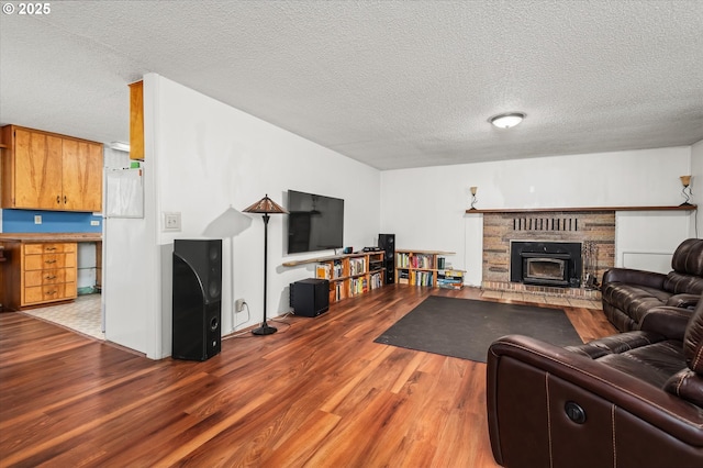 living area featuring a textured ceiling, a fireplace, and wood finished floors